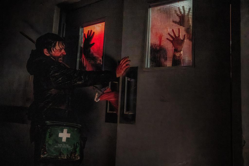 Escena de Resident Evil Noche Cero, el personaje esta sosteniendo una puerta para que los zombies no entren, se encuentra en el interior de un hospital